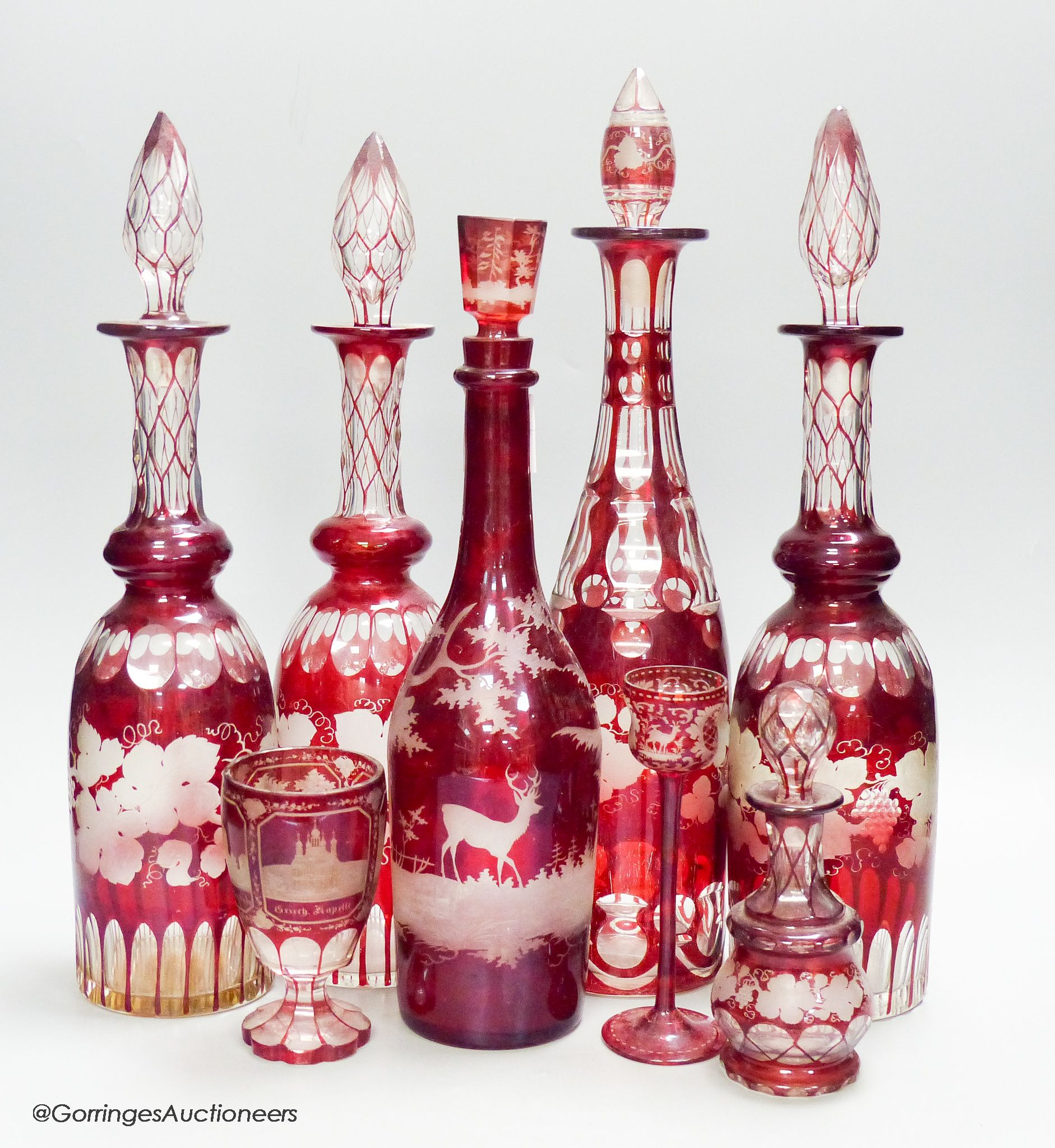 A collection of six Bohemian ruby flashed wheel engraved glass decanters, tallest 40cm, a similar spa beaker and liqueur glass